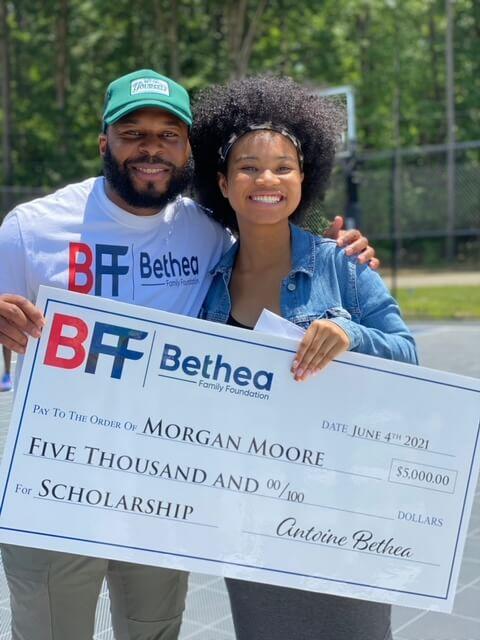 Bethea giving check to woman on basketball court 