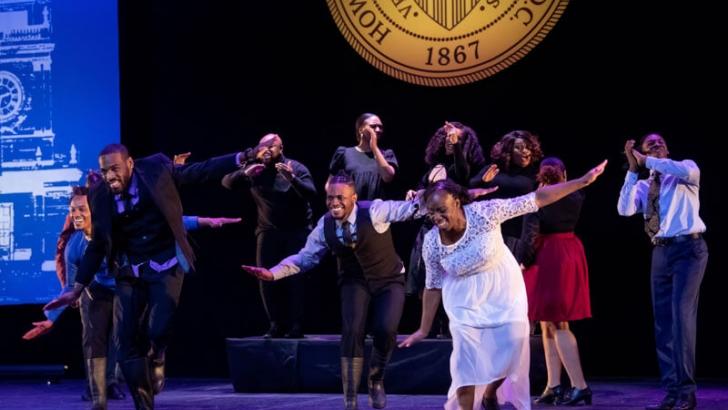 People standing on stage with arms out wide