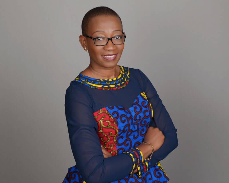 Dr. Dawuni sitting on a stool with her arms crossed