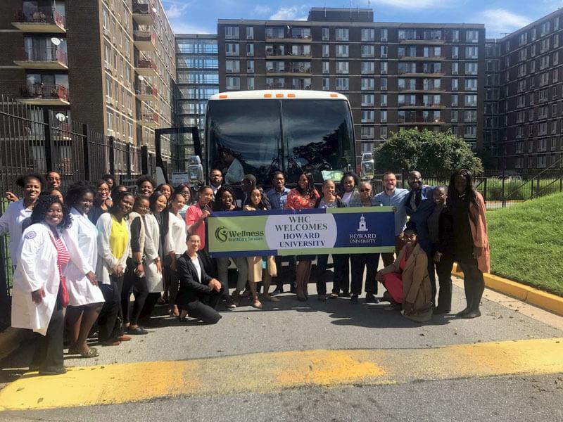 Bus with people in front of it holding a Howard welcome sign