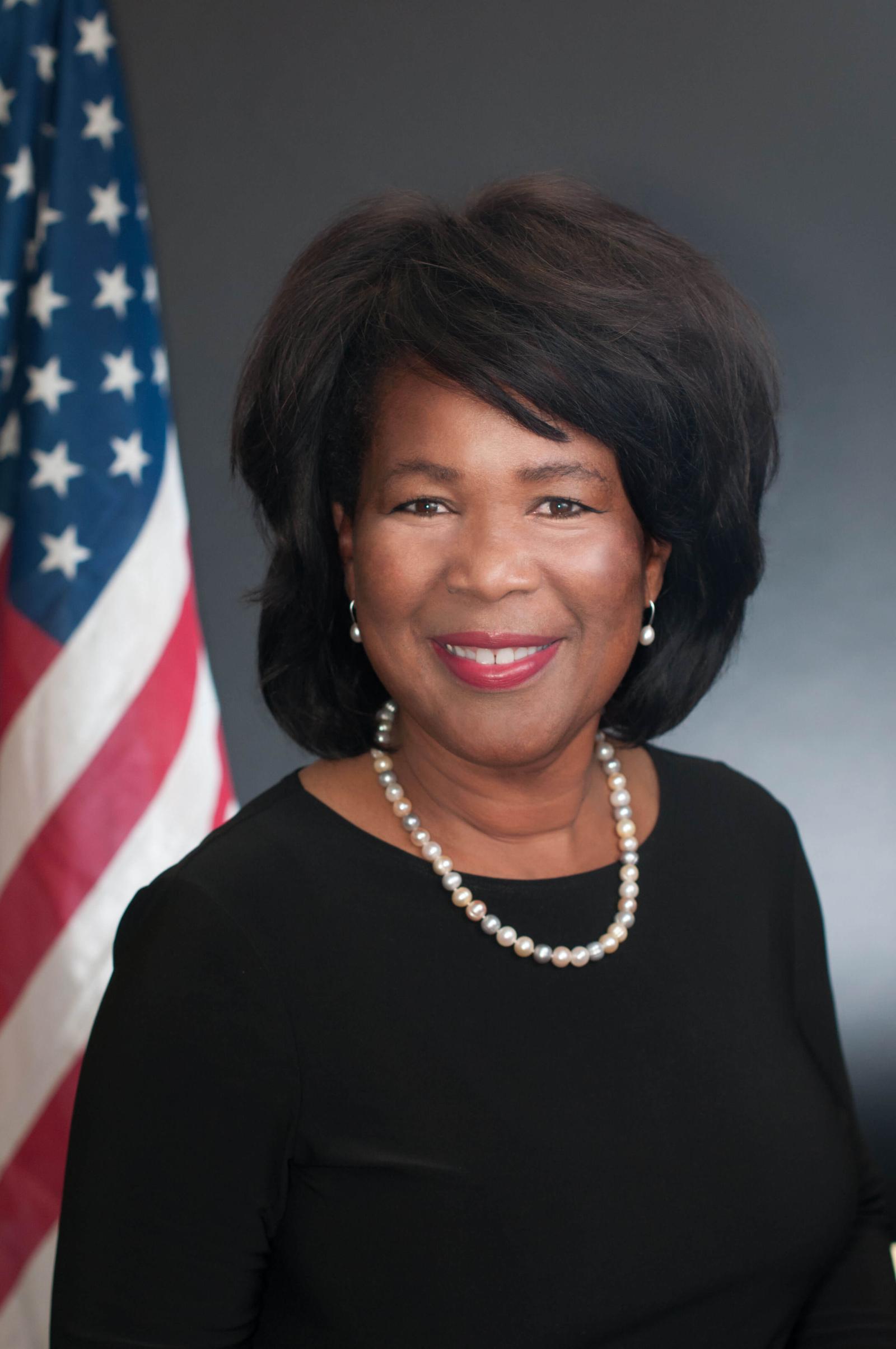 Peggy Carr headshot with flag in the background