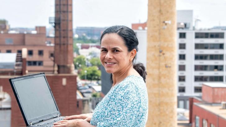 Claudia Marin with her laptop open on the roof of a city building