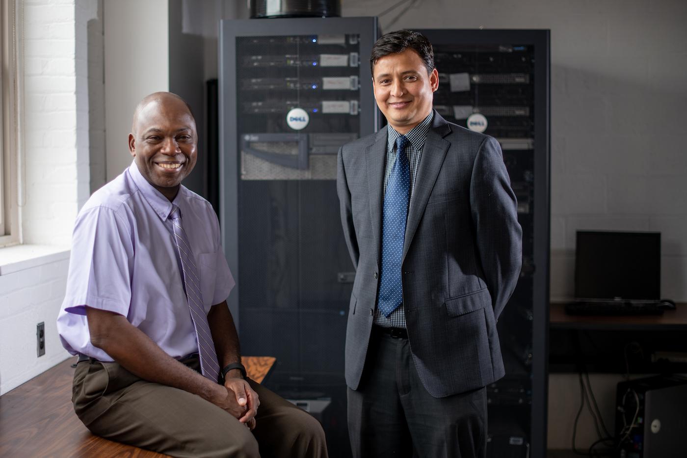 Two scientists in suits standing in front of computer server