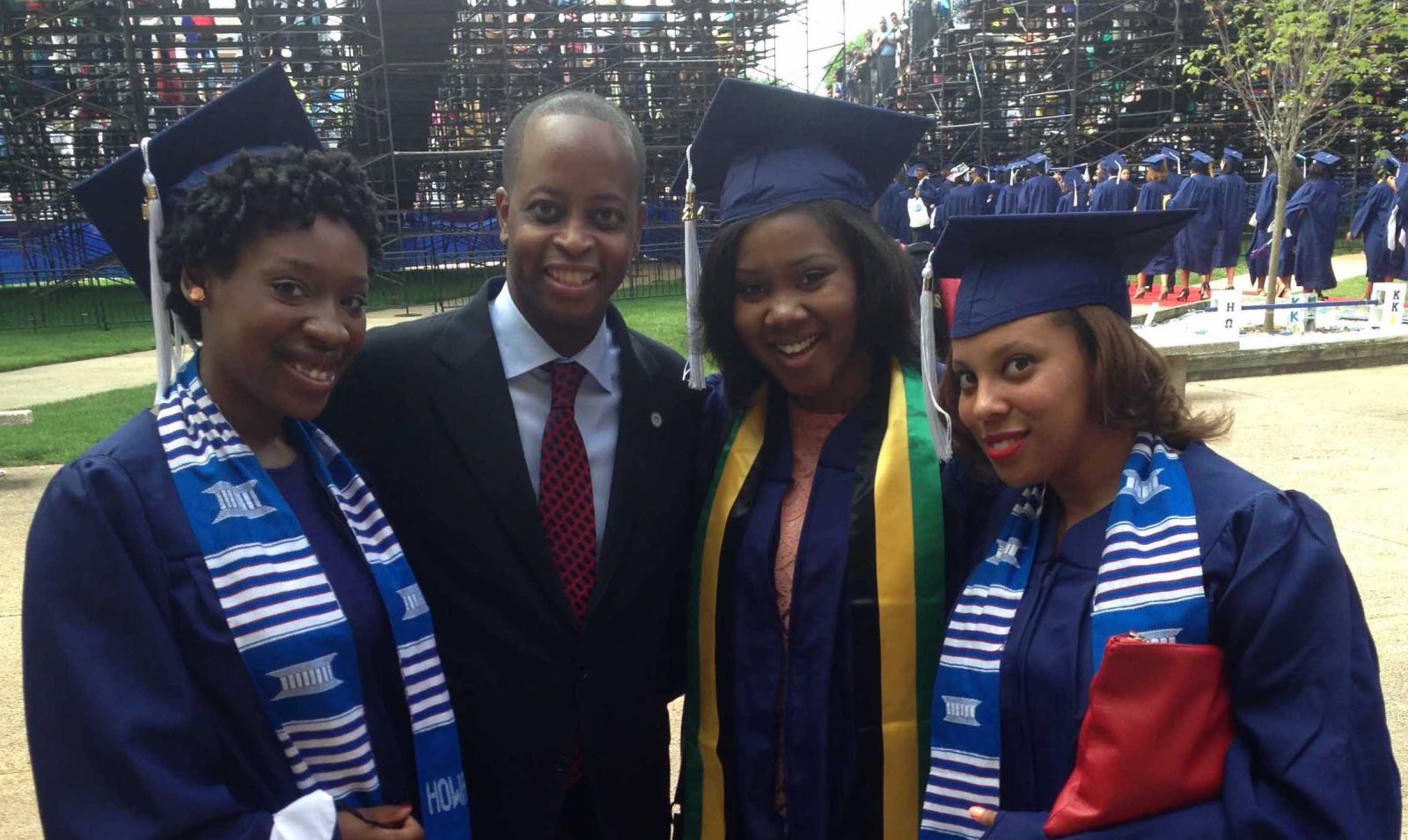 Three students in regalia with president Frederick