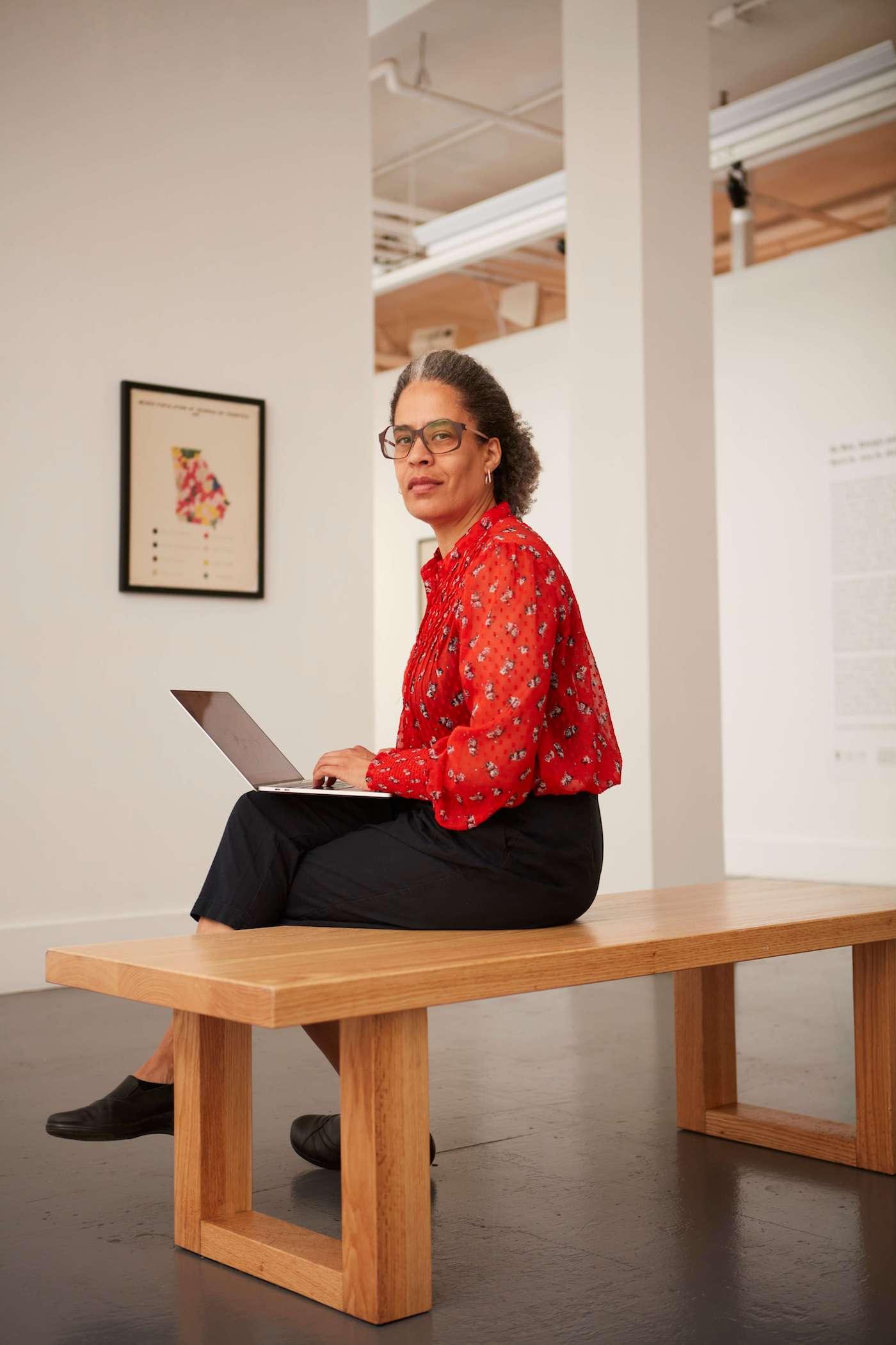 Lisa Dent sitting on a desk with a laptop