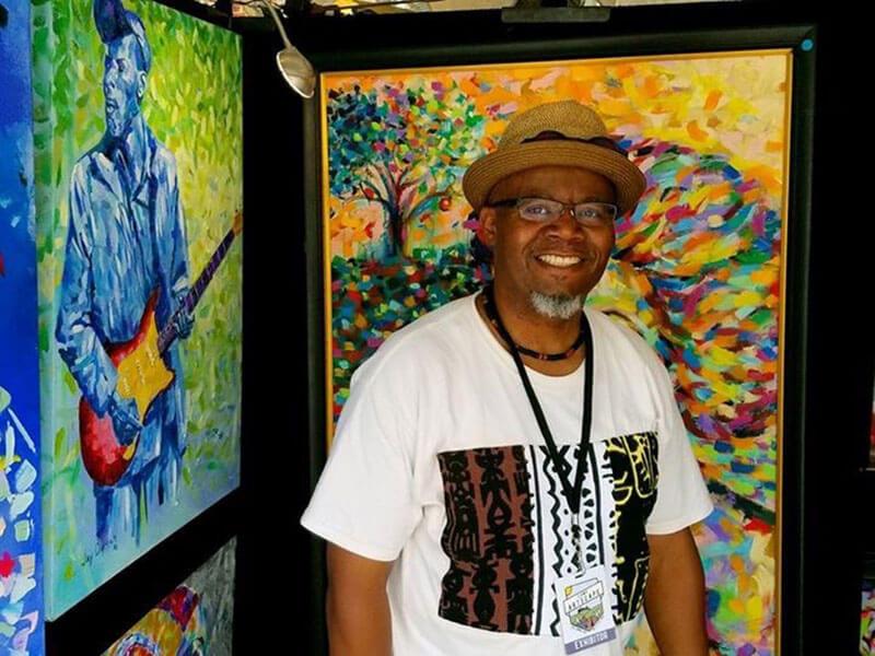 Jay Durrah standing in front of his art