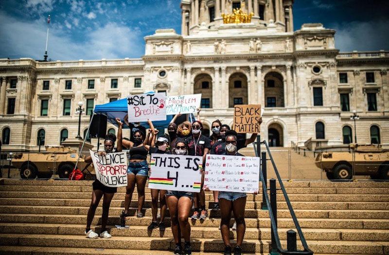 Protestors on steps with signs