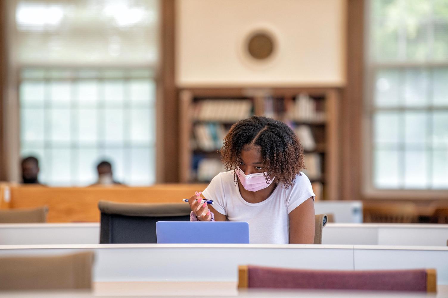 Female student in library working on laptop