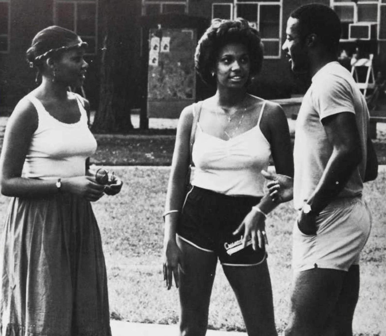 three people standing around in 1980s photo