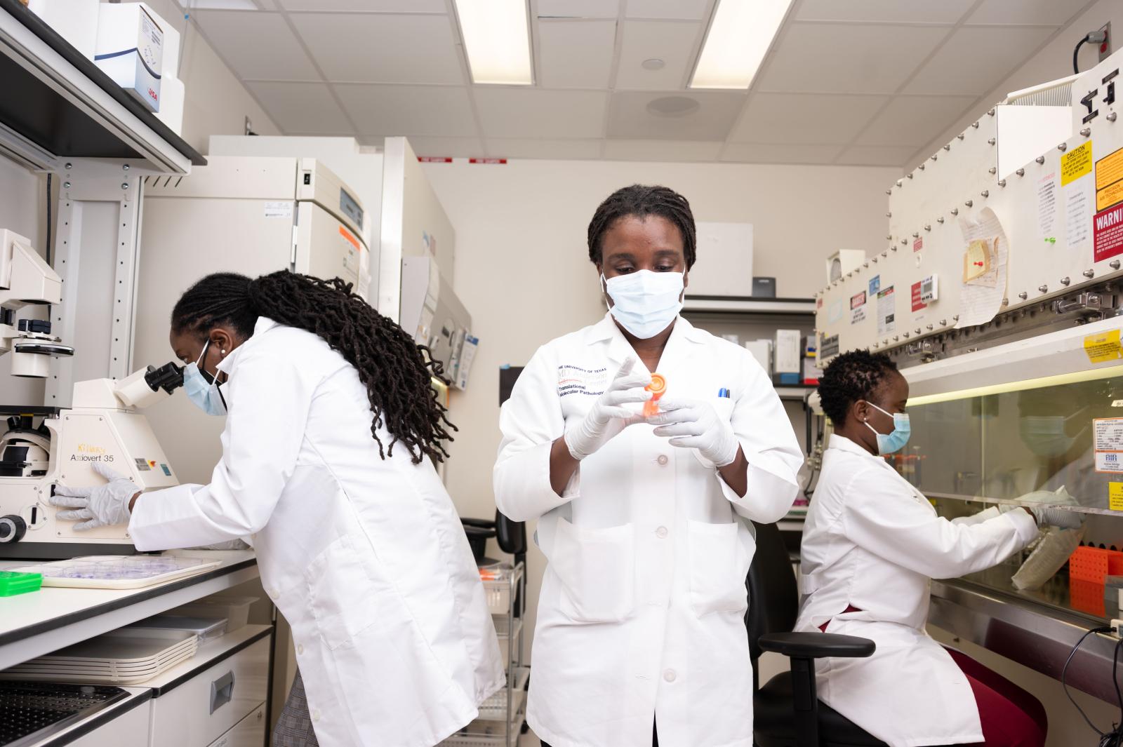 three researchers in masks and lab coats 