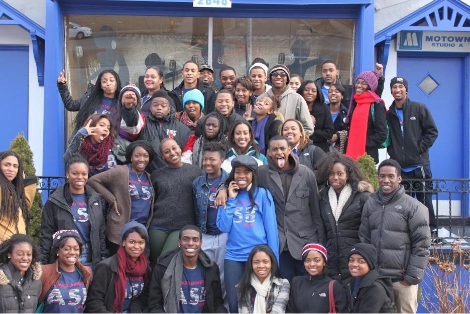 group of students in winter clothing outside of a church smiling