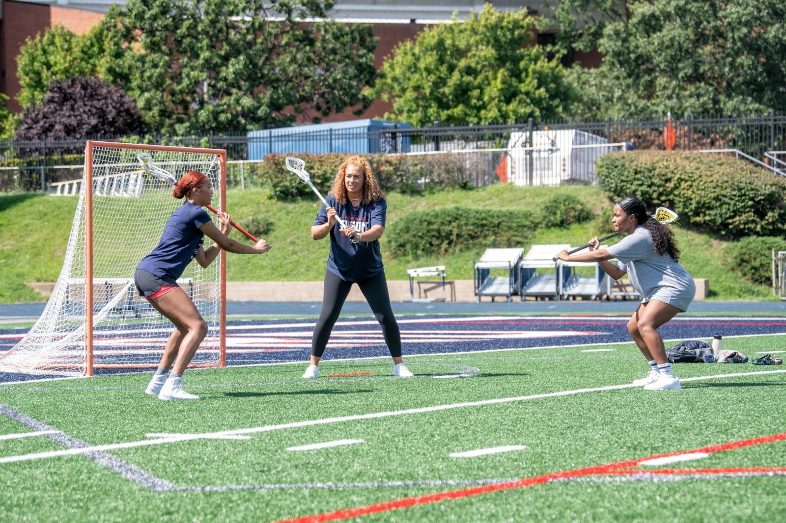 lacrosse coach with two lacrosse players outside