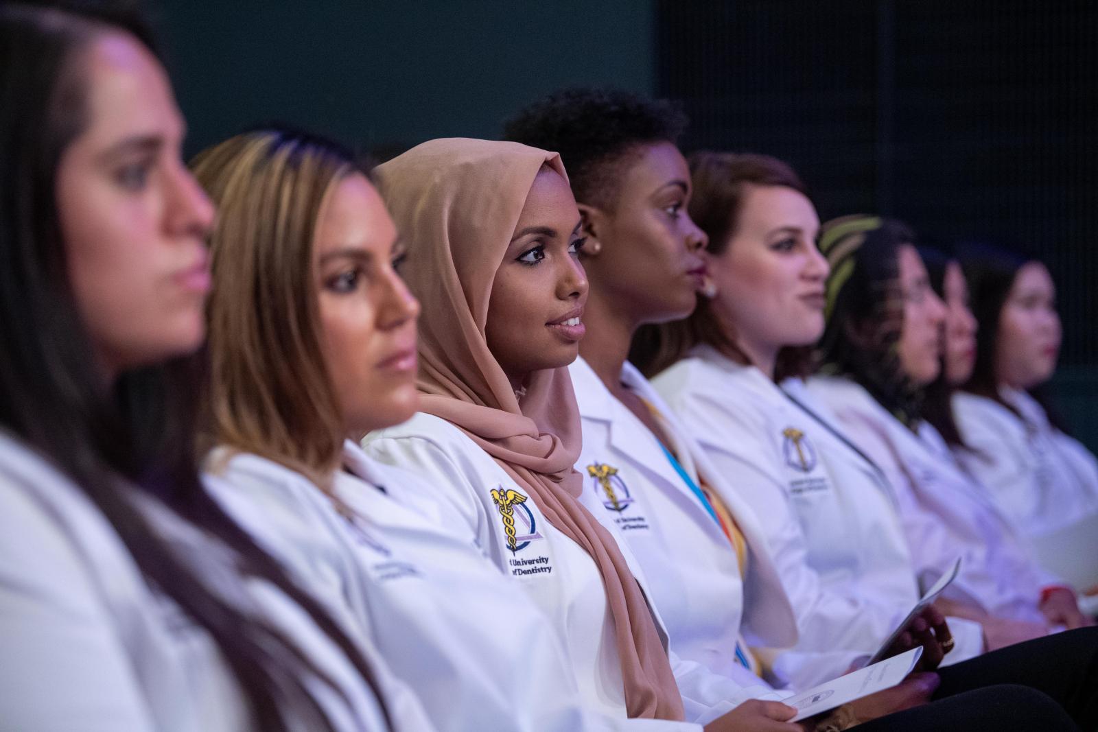 women dental students in white coats sitting