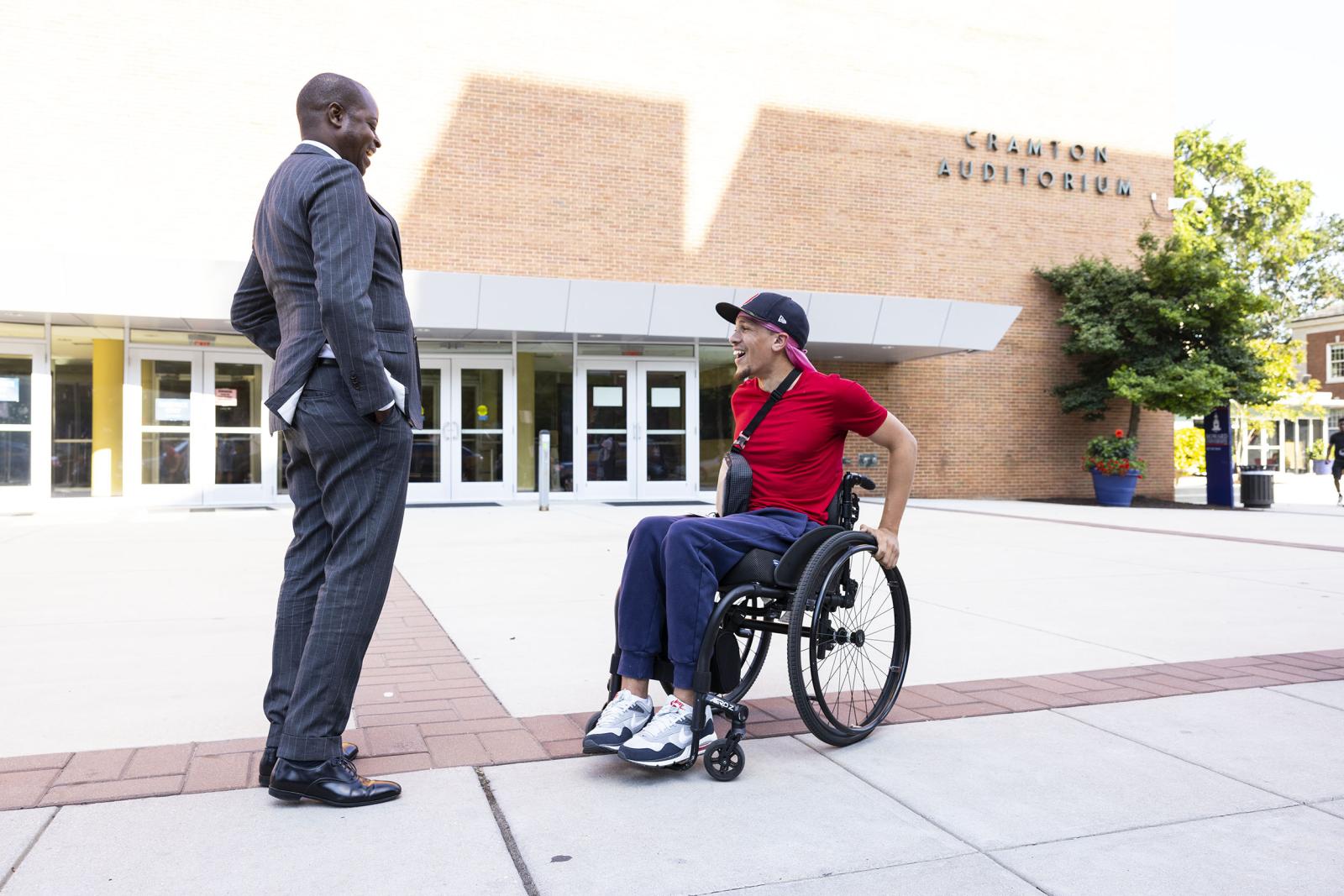 Dr. Frederick with student in red shirt and wheelchair outside