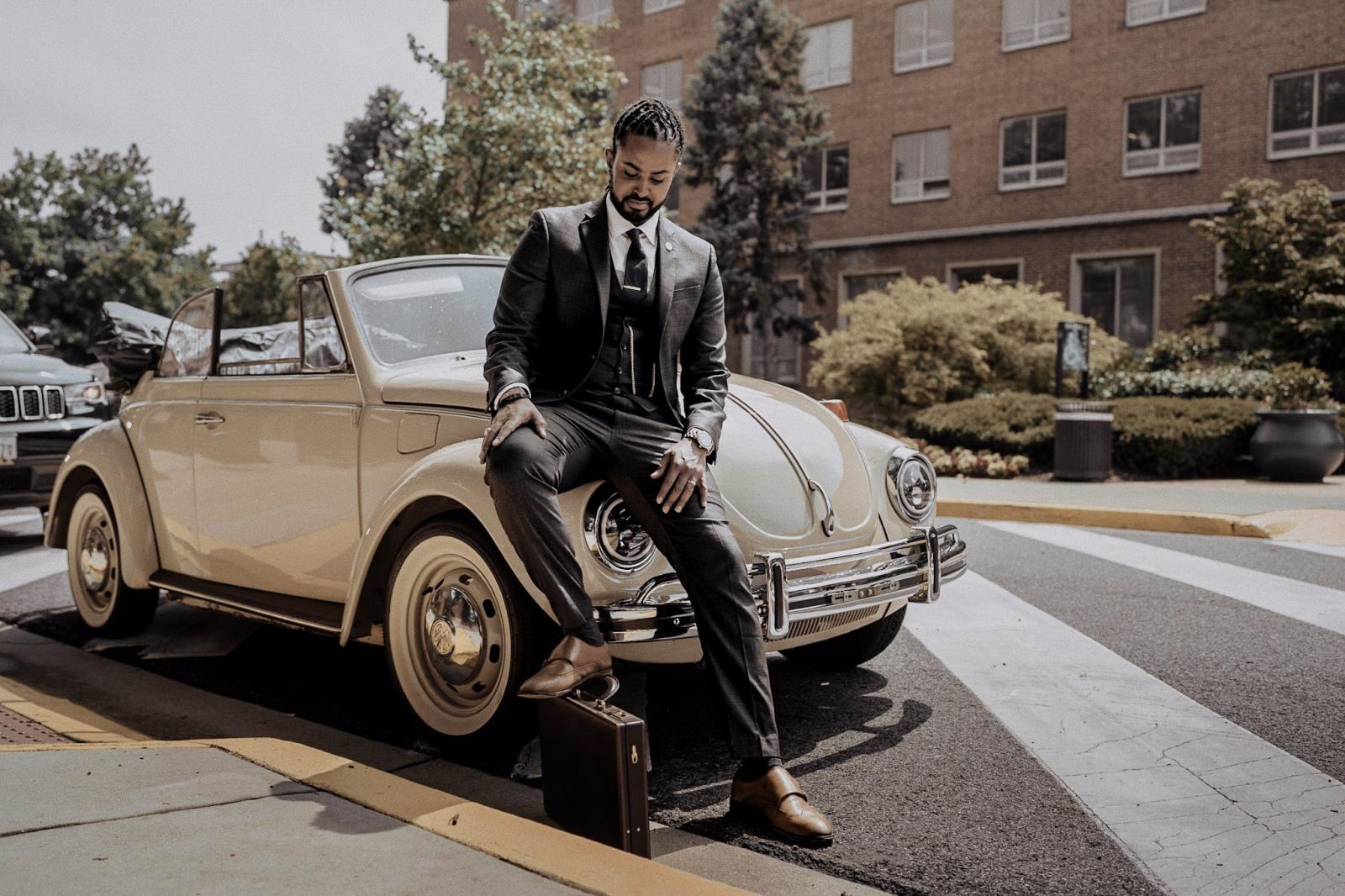 Debebe sitting on restored white VW beetle