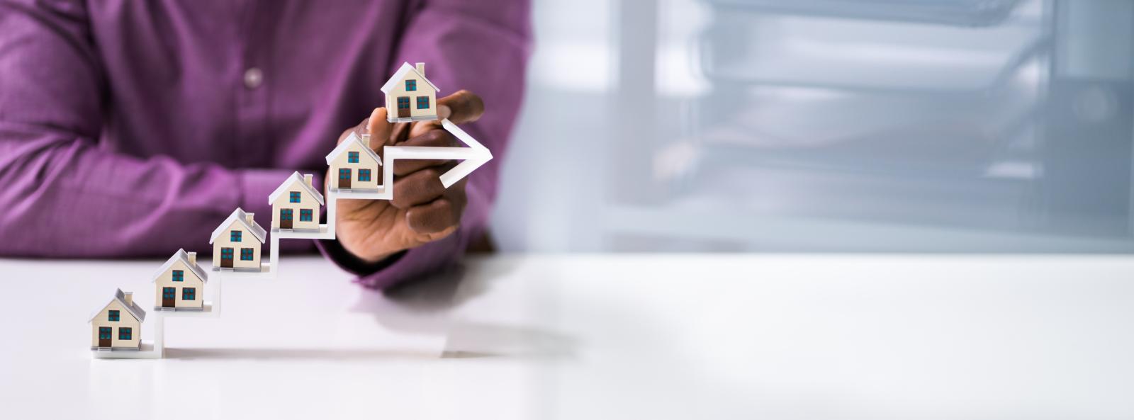 person's hand with houses on a climbing arrow