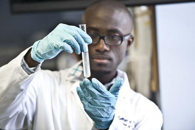 A Howard University researcher observes a vial. 