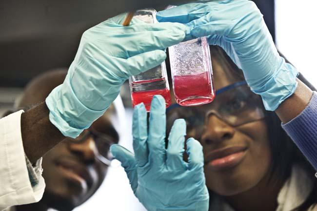 Two Howard University researchers look at red liquid in vials.