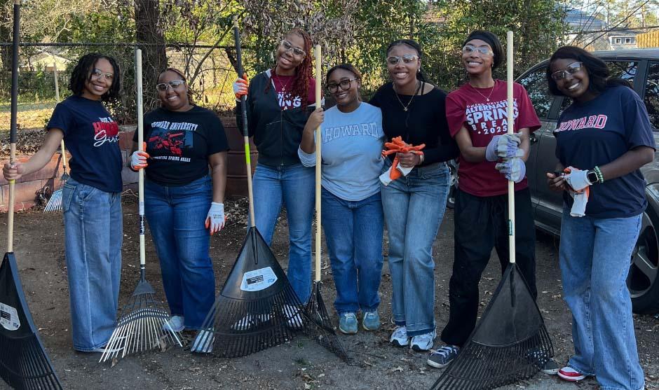 Alternative Spring Break volunteers working outside. Everyone is holding rakes