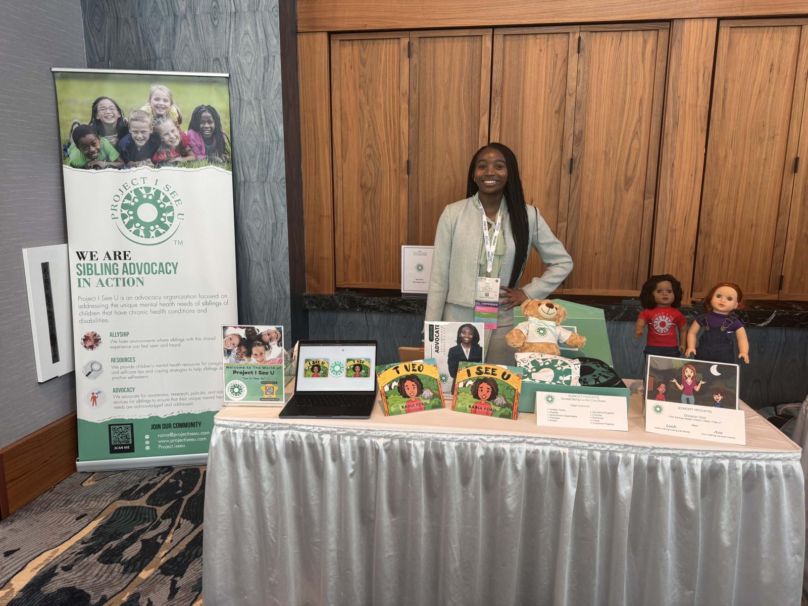 Raina Ford standing behind a table with her books and other products