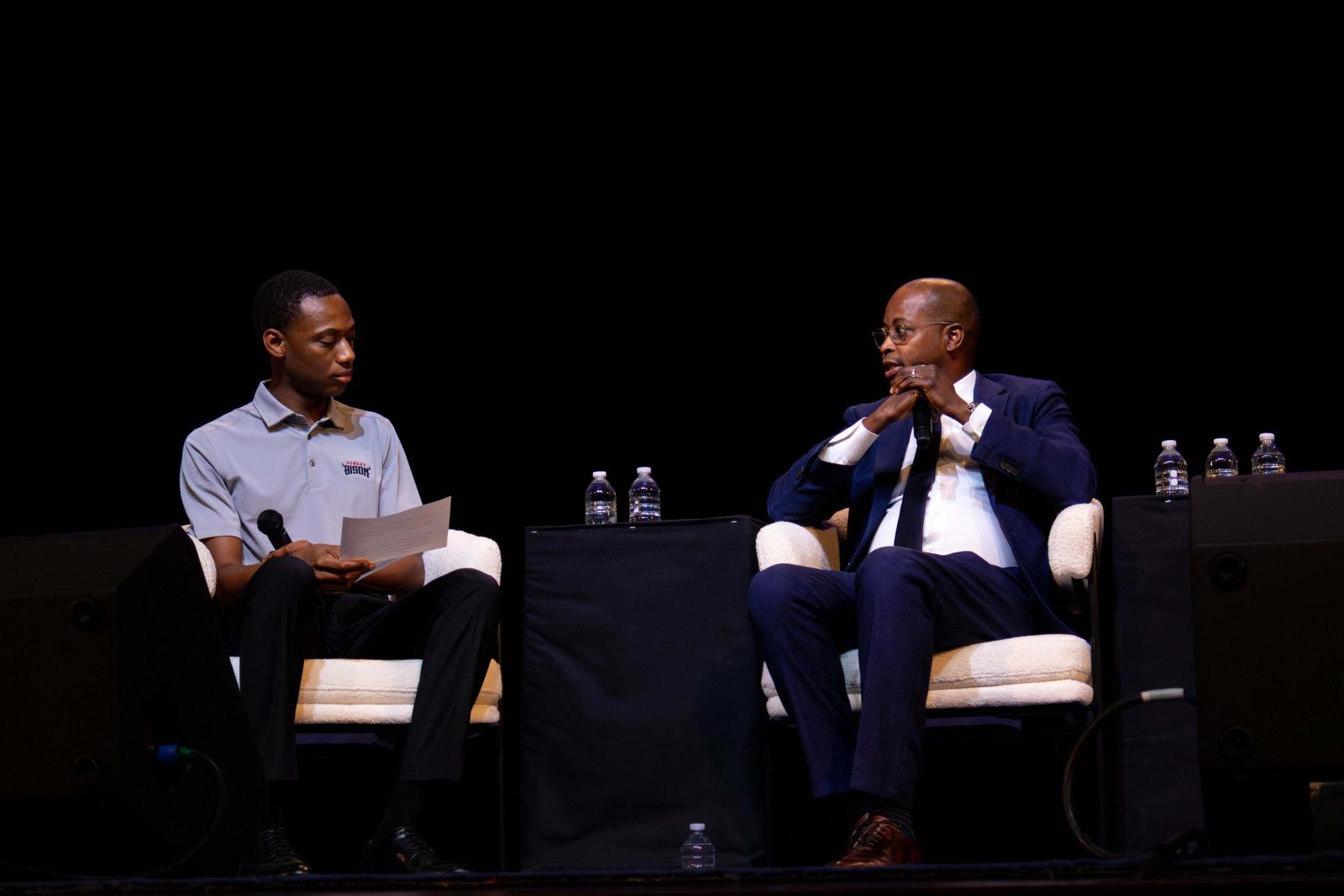 President Frederick on the right and a student on the left sitting on a stage talking